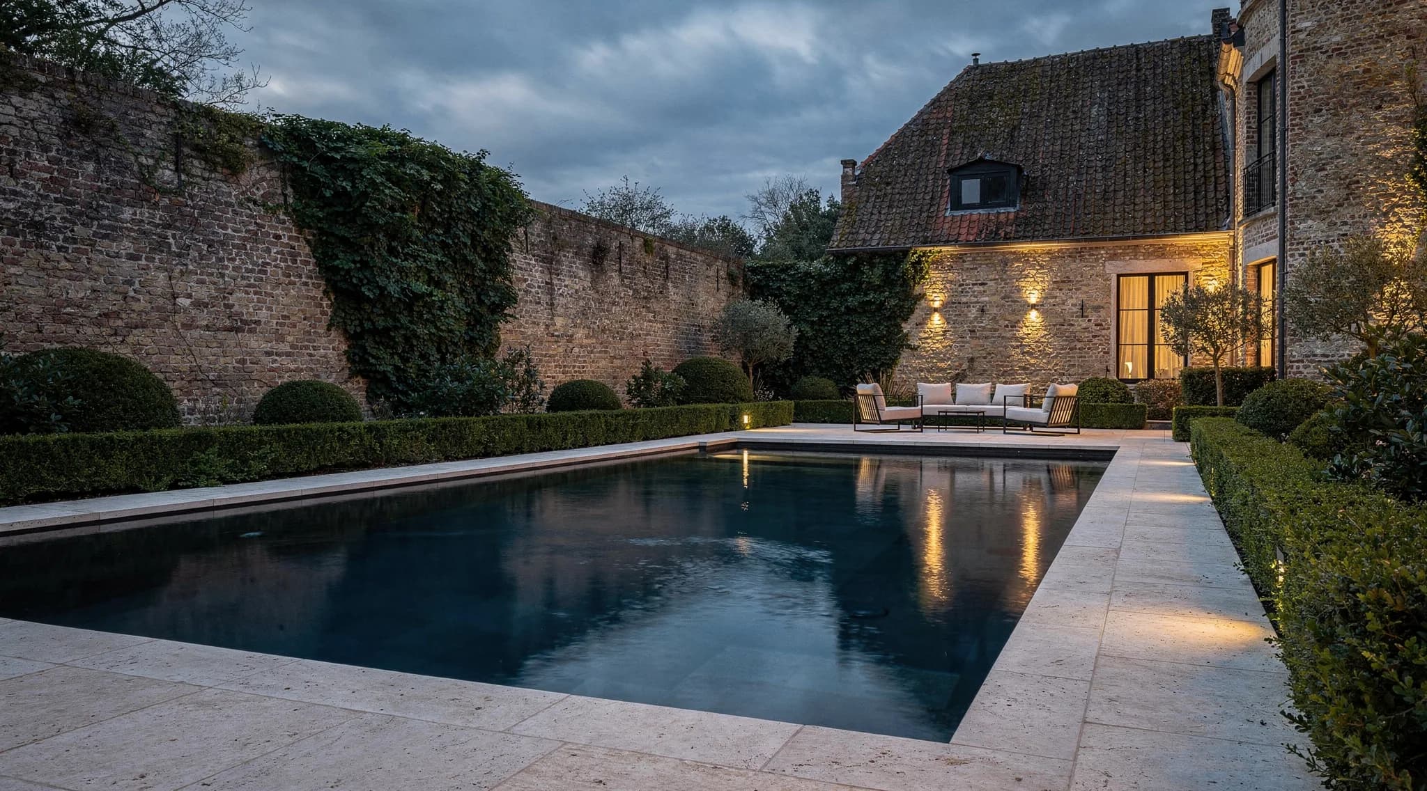 Conceptbeeld van een privaat zwembad bij een Vlaamse villa tijdens het blauwe uur, met warme architecturale verlichting